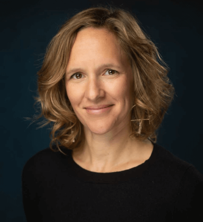 Headshot of a smiling woman with wavy shoulder-length hair wearing a black top.