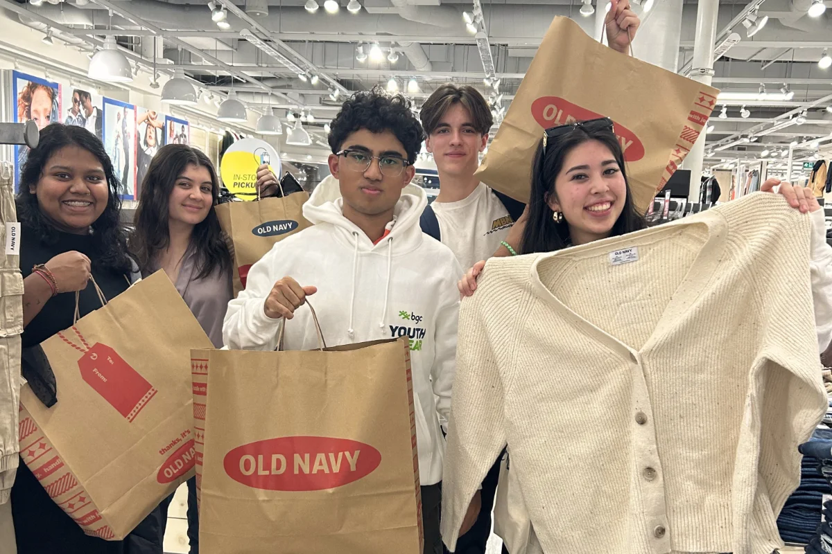 Youth participants from BGC Clubs holding shopping bags and clothing during a visit to an Old Navy store.