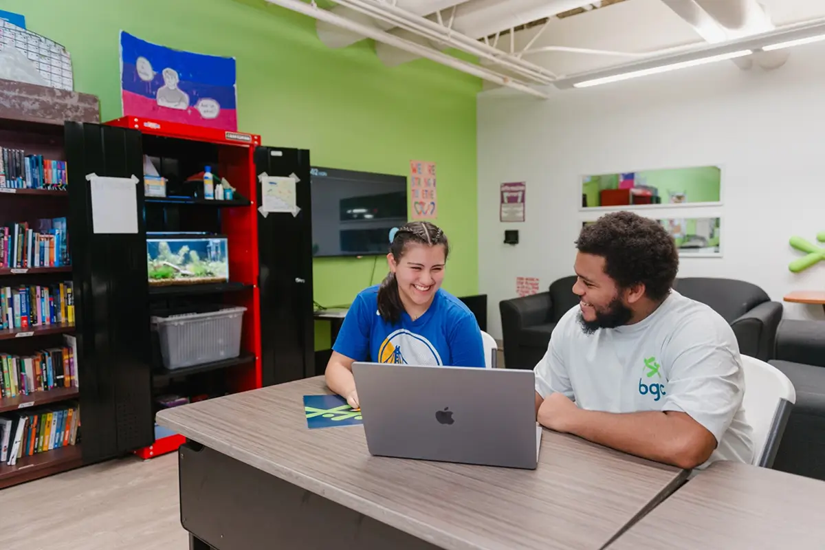Two youth smiling and working together on a laptop at a BGC Club