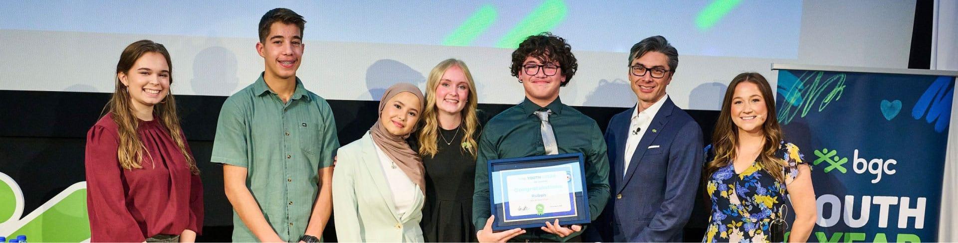 Group of people at a BGC Youth of the Year awards ceremony, with one holding a framed certificate.