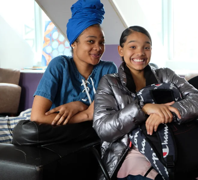 Two people sitting together indoors, smiling and spending time in a supportive environment.