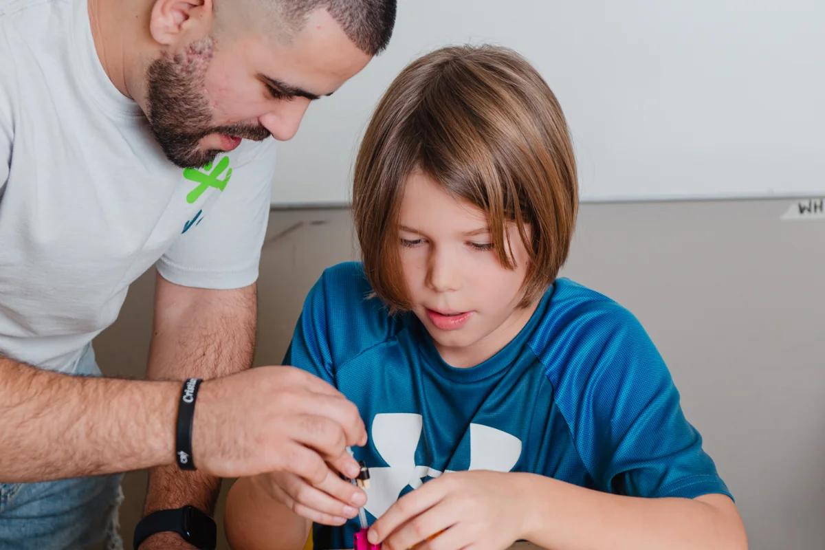 An adult guiding a child during a hands-on learning activity at a table.