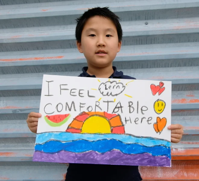 Young boy holding a drawing that says "I feel comfortable here."