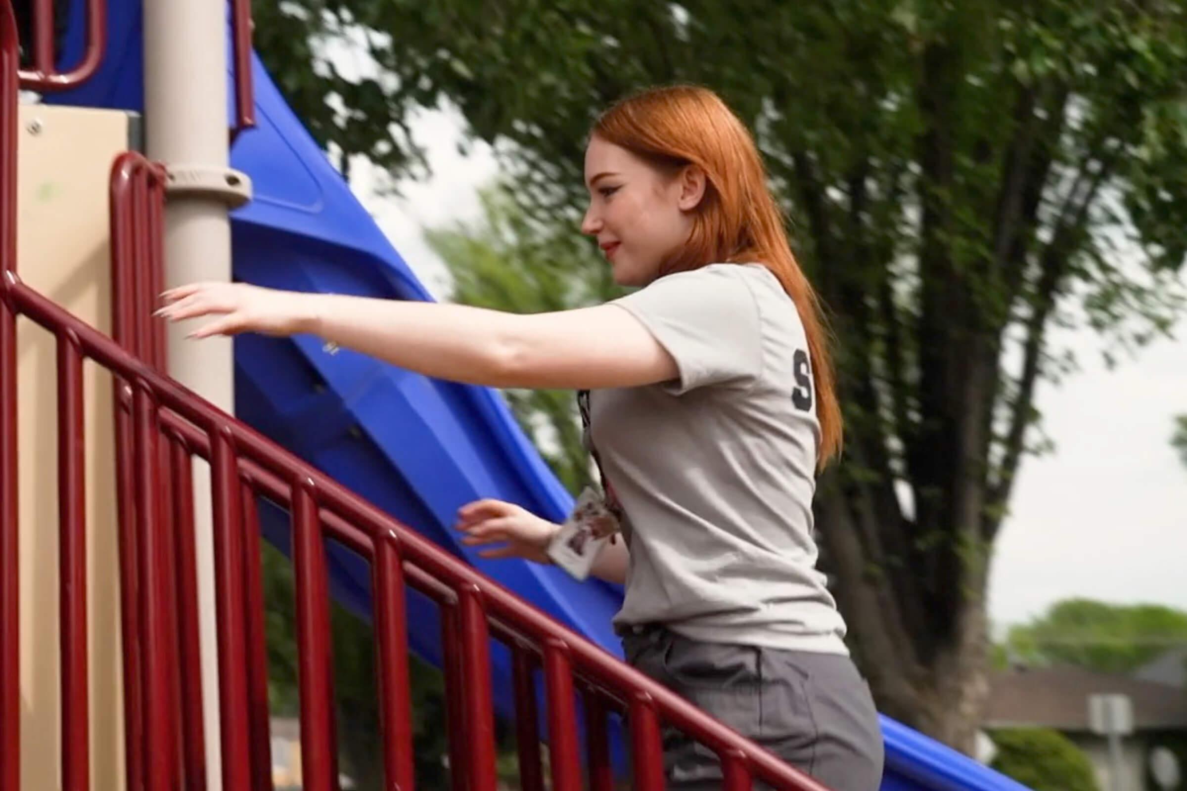 Yaël standing on playground steps outdoors.