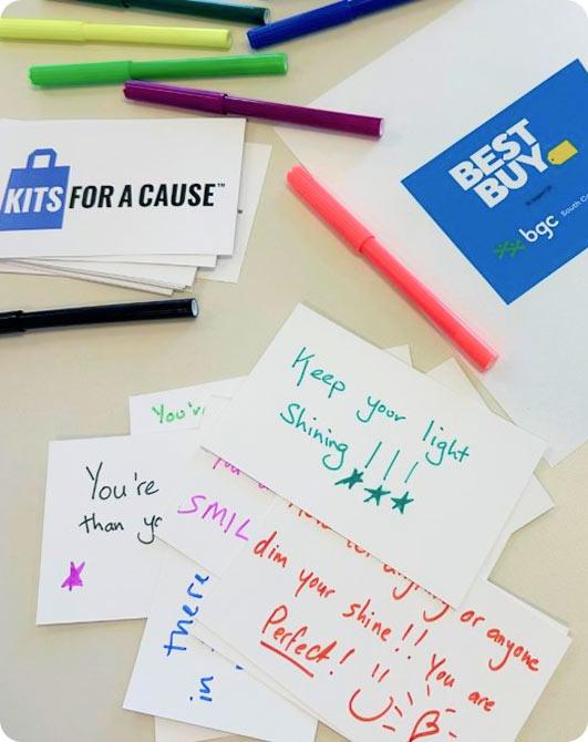 Handwritten motivational cards scattered on a table alongside colorful markers and brand logos.