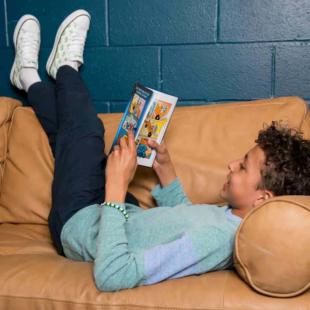 A child reading a comic book while relaxing on a couch.