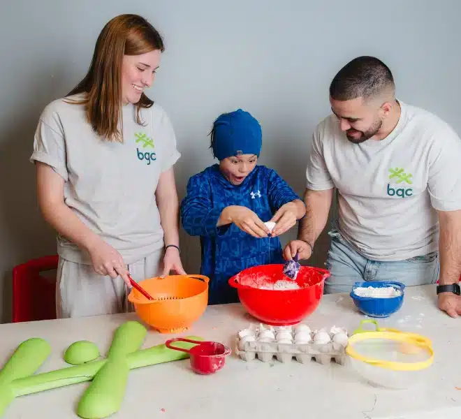 Two BGC staff members helping a child prepare food during a Club activity.